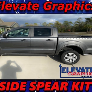 May include: A grey Ford Ranger pickup truck with black side steps and a black bed liner. The truck has a set of grey and black side spear decals. The decals have a diagonal stripe pattern. The truck is parked on a grey concrete surface. The image includes the text "Elevate Graphics" and "Side Spear Kit".