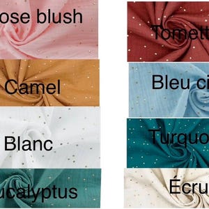 Op de afbeelding: Een verzameling stofstalen in verschillende kleuren, waaronder roze blush, camel, wit, eucalyptus, tomette, lichtblauw, turquoise en ecru. Elk staal heeft een subtiel patroon van gouden glitterdots.