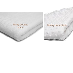 Op de afbeelding: Twee witte minky stoffen. E&eacute;n is glad en de andere heeft kleine witte stippen. De tekst "Minky doudou blanc" staat op de gladde stof en de tekst "Minky pois blanc" staat op de stof met stippen.