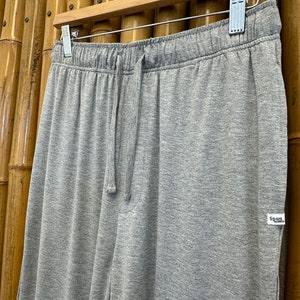 May include: Gray sweatpants with a drawstring waist and a small white tag that says "Spun" on the right side.