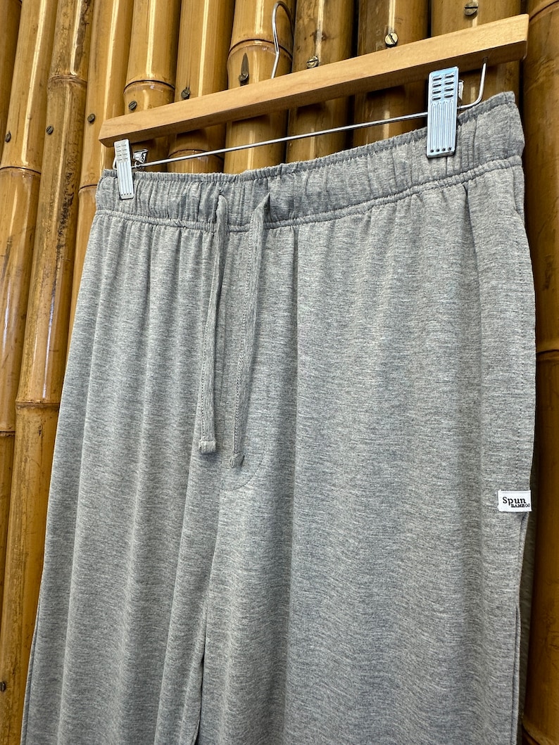 May include: Gray sweatpants with a drawstring waist and a small white tag that says "Spun" on the right side.
