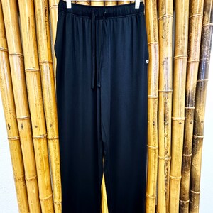 May include: Black drawstring pants with a relaxed fit. The pants have a simple design and are made of a soft, comfortable fabric.