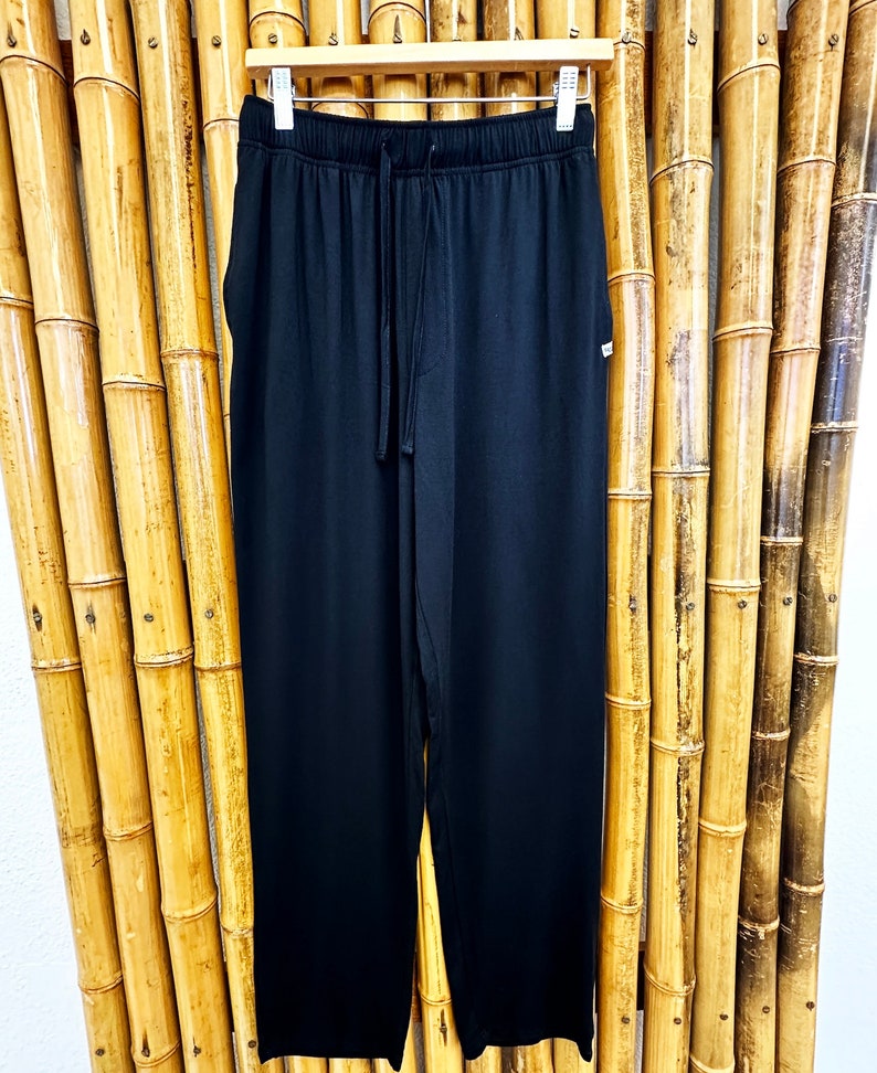 May include: Black drawstring pants with a relaxed fit. The pants have a simple design and are made of a soft, comfortable fabric.