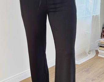 Könnte beinhalten: Schwarze Hose mit Kordelzug und ausgestellten Beinen. Die Hose hat ein schlichtes Design mit leicht ausgestelltem Beinabschluss. Der Stoff scheint weich und bequem zu sein. Geeignet für Freizeitkleidung.