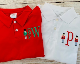 May include: Two red and white polo shirts with embroidered nutcracker designs and the letters "EW" and "p".