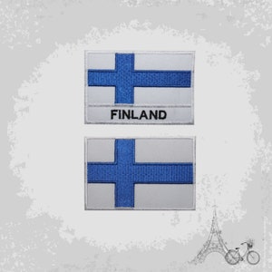 May include: Two embroidered patches featuring the Finnish flag. The top patch has the word "FINLAND" written below the flag. Both patches are white with a blue cross.