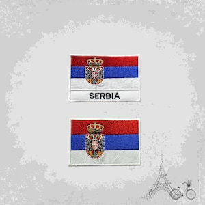 Pode incluir: Dois patches bordados com a bandeira da Sérvia. O patch superior tem a palavra "SERBIA" impressa abaixo da bandeira. Ambos os patches são brancos com detalhes vermelhos, azuis e dourados.