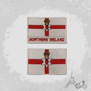 May include: Two white embroidered patches featuring the Northern Ireland flag. The flag depicts a red cross on a white background with a red hand and a gold crown at the centre. The text "NORTHERN IRELAND" is embroidered on the top patch.