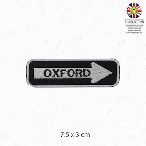 May include: Black and white embroidered iron-on patch with the word "OXFORD" and a white arrow pointing to the right. The patch is 7.5 cm by 3 cm.