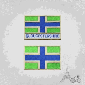 Könnte beinhalten: Zwei gestickte Aufnäher mit der Flagge von Gloucestershire. Die Flagge ist grün mit einem blauen Kreuz und weißem Rand. Der obere Aufnäher trägt die Aufschrift "GLOUCESTERSHIRE" in weiß.