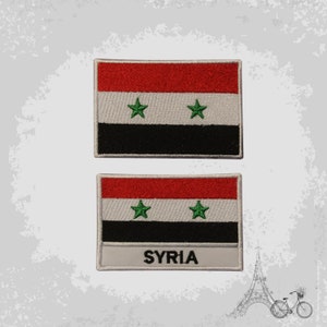 May include: Two embroidered patches of the Syrian flag. The flag is red, white, and black with three green stars. The bottom patch has the word "SYRIA" printed below the flag.