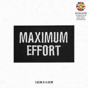 以下が含まれることがあります： 白文字で「MAXIMUM EFFORT」と刺繍された黒いアイロン接着パッチ。パッチのサイズは7.5cm x 4.5cmです。