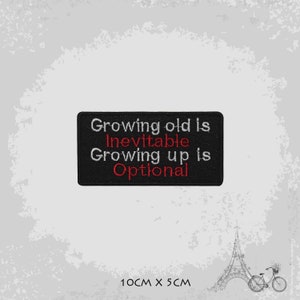 Peut inclure: Patch brodé noir avec du texte blanc qui dit "Growing old is Inevitable Growing up is Optional". Le texte "Inevitabile" et "Optional" est en rouge. Le patch mesure 10 cm sur 5 cm.