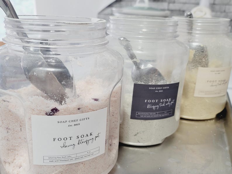 May include: Three clear plastic jars filled with different colored bath salts. The jars have labels that say "Soap Chef Gifts Est. 2019" and "Foot Soak Relaxing, Detoxifying  Pot".