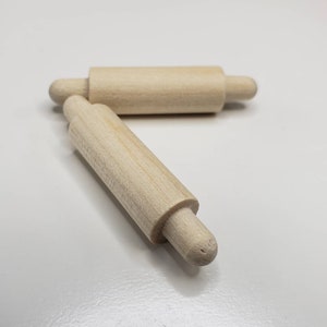 Puede incluir: Dos clavijas de madera con extremos redondeados. Las clavijas son sin terminar y de color natural.
