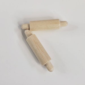 Puede incluir: Dos rodillos de amasar de madera con extremos redondeados. Los rodillos de amasar son de madera natural y miden aproximadamente 15 cm de largo.