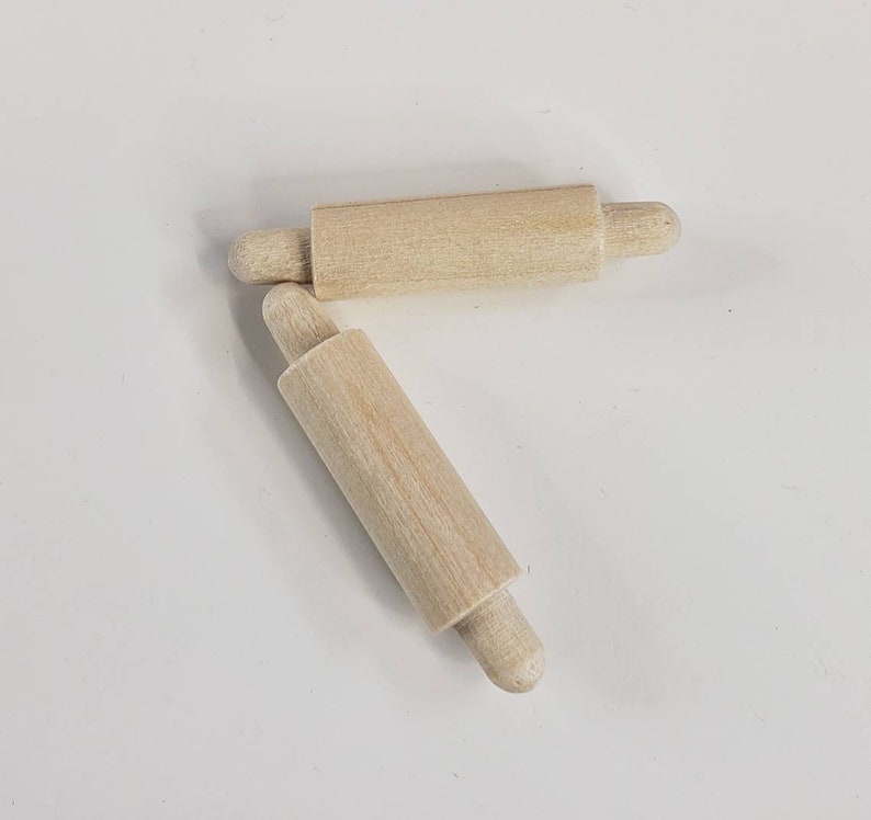 Puede incluir: Dos rodillos de amasar de madera con extremos redondeados. Los rodillos de amasar son de madera natural y miden aproximadamente 15 cm de largo.
