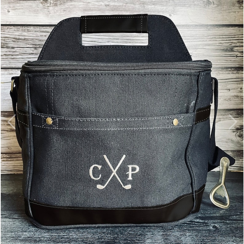 May include: A black canvas cooler bag with a zippered top, a handle, and a shoulder strap. The bag has a bottle opener attached to the strap. The bag has a monogram with the initials "CXP" and two crossed golf clubs.