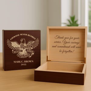 May include: A wooden box with a dark brown exterior and a light brown interior. The box is open, revealing an inscription. The exterior features an eagle design with the words "Courage Never Retires." The interior reads, "Thank you for your service."