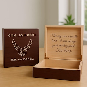 May include: A wooden box with a dark brown exterior and a light brown interior. The lid of the box features the text "CMM. JOHNSON" above a U.S. Air Force emblem and the words "U.S. AIR FORCE". The inside lid has the quote "The sky was never the limit - it was always your starting point. Keep flying."