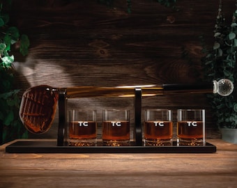 Puede incluir: Un soporte de madera para palos de golf con cuatro vasos pequeños llenos de líquido marrón. Los vasos están grabados con las letras "TC".