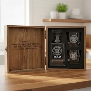 May include: A wooden gift box containing a clear glass decanter and two matching glasses. The decanter and glasses feature the United States Navy emblem and the name TOMAS. The inside lid is engraved with: TOMAS, THANK YOU FOR YOUR SERVICE. NOW ITS TIME TO SIT BACK AND ENJOY RETIREMENT!