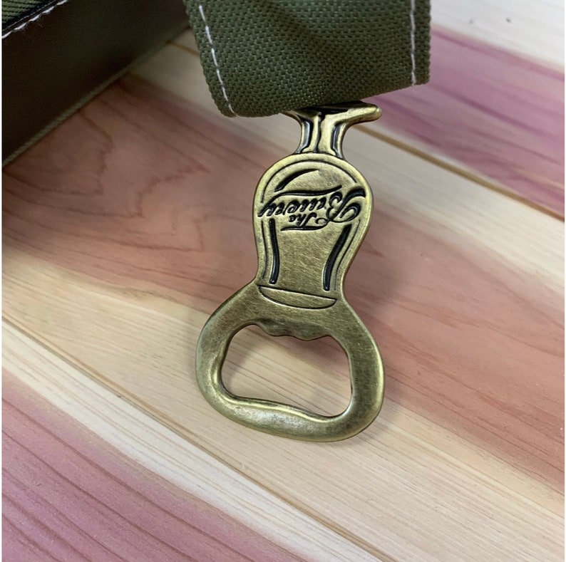 May include: A gold-colored bottle opener with a black inscription that reads "Tommy's NYC".