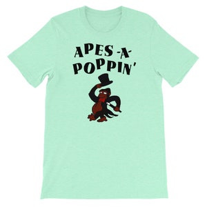 May include: A light green t-shirt featuring a black graphic of a monkey wearing a top hat and holding a cane. The text "APES-A-POPPIN'" is above the monkey.