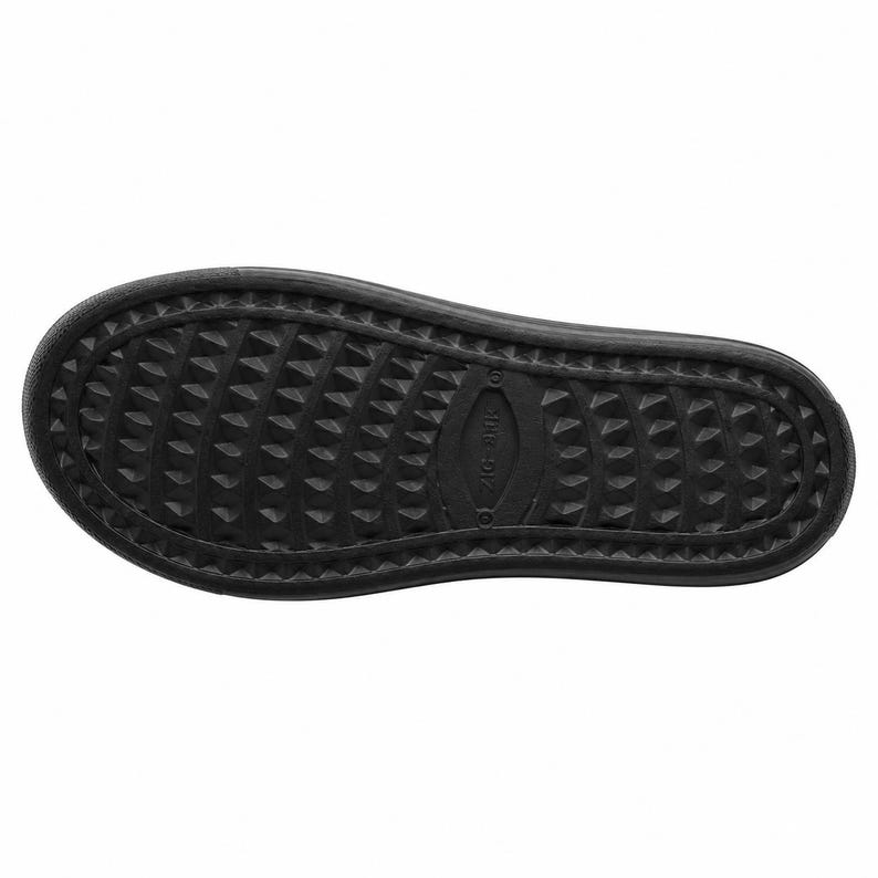 May include: A close-up of the bottom of a black shoe. The sole features a textured pattern of small, evenly spaced, triangular shapes. The shoe's design includes a slightly raised edge and a central oval-shaped detail.