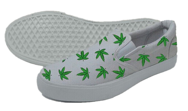 May include: White slip-on canvas shoes with a green marijuana leaf pattern.