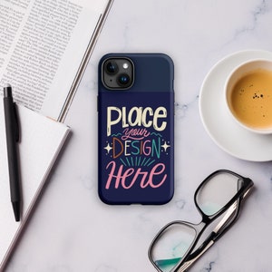 May include: Navy blue phone case with the text "Place your DESIGN Here" in a colorful, whimsical font. The case has a dark blue top and a dark blue bottom with the text. A cup of coffee, glasses, and a pen are also visible.