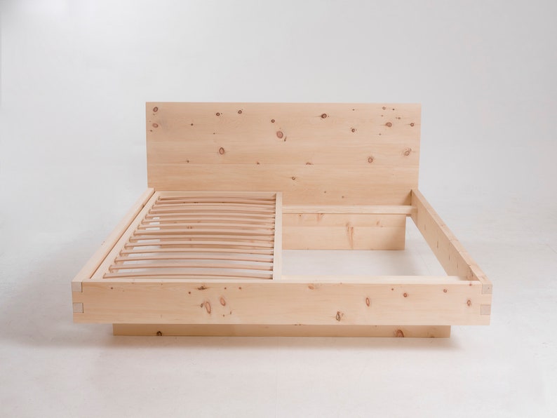 K&ouml;nnte beinhalten: Ein Holzbettgestell mit einem Lattenrost-Kopfteil und einem Lattenrost-Fu&szlig;teil. Der Rahmen ist aus Naturholz mit einer hellbraunen Oberfl&auml;che.