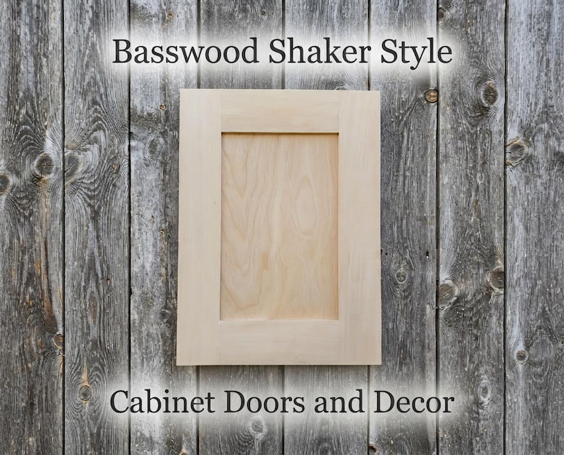 May include: A light-colored, unfinished basswood cabinet door with a flat center panel and a rectangular frame. The text Basswood Shaker Style and Cabinet Doors and Decor is visible above and below the wooden cabinet door.