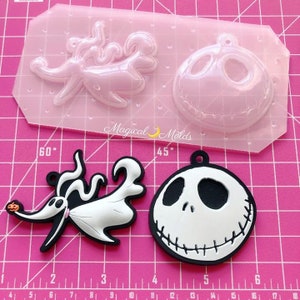 Puede incluir: Un molde de silicona rosa con dos cavidades, una con un personaje con cabeza redonda y boca cosida, y la otra una figura fantasmal. Debajo hay dos productos terminados: un Zero y un Jack Skellington en blanco y negro.