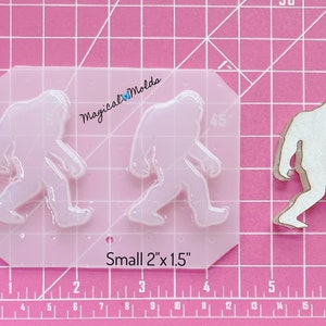 May include: A clear silicone mould with two Bigfoot footprints. The mould is 2 inches by 1.5 inches. The text "Magical WMolds" and "Small 2"x 1.5"" is visible on the mould.