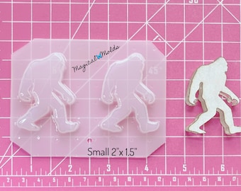 Könnte beinhalten: Eine transparente Silikonform mit zwei Bigfoot-Fußabdrücken. Die Form ist 5,1 cm x 3,8 cm groß. Der Text "Magical WMolds" und "Small 2"x 1.5"" ist auf der Form sichtbar.
