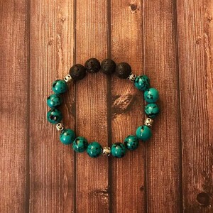 Puede incluir: Un brazalete hecho de roca de lava negra y cuentas de turquesa con separadores de plata.