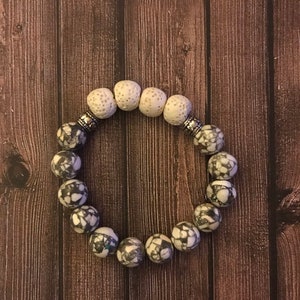 Puede incluir: Un brazalete hecho de cuentas blancas y negras moteadas con detalles plateados.