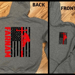 May include: Gray hooded sweatshirt with a red, white, and blue American flag design. The flag has a silhouette of a lineman climbing a utility pole. The text "FARNAM" is printed vertically on the left side of the flag.