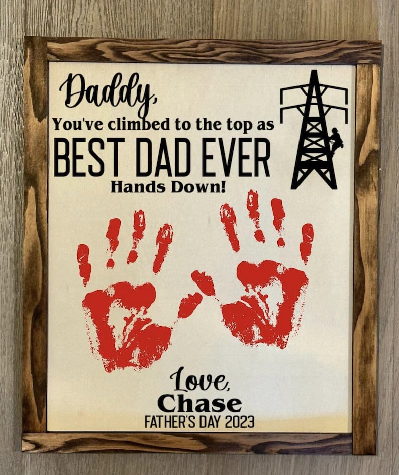May include: A framed sign with a hand-painted message that reads "Daddy, You've climbed to the top as BEST DAD EVER Hands Down!" with two red handprints and the text "Love, Chase FATHER'S DAY 2023".
