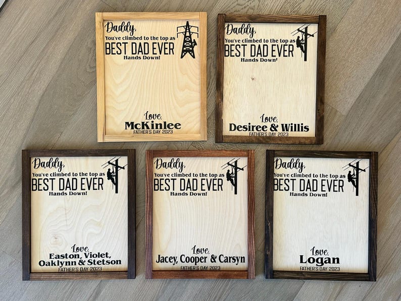 May include: Five wooden signs with a brown frame and a white background. Each sign features a silhouette of a lineman climbing a utility pole. The signs have the text "Daddy, You've climbed to the top as BEST DAD EVER Hands Down!" and a personalized message with the name and year.