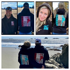 May include: A couple wearing black hoodies with a distressed American flag design on the back. The hoodies have the text "FARINAM" printed on the left side of the flag and a graphic of a lineman climbing a utility pole. The woman's hoodie has a turquoise blue and pink color scheme, while the man's hoodie has a red and white color scheme. The woman's hoodie also has the text "LINE BABE" printed on the front. The couple is standing on a beach with the ocean in the background.