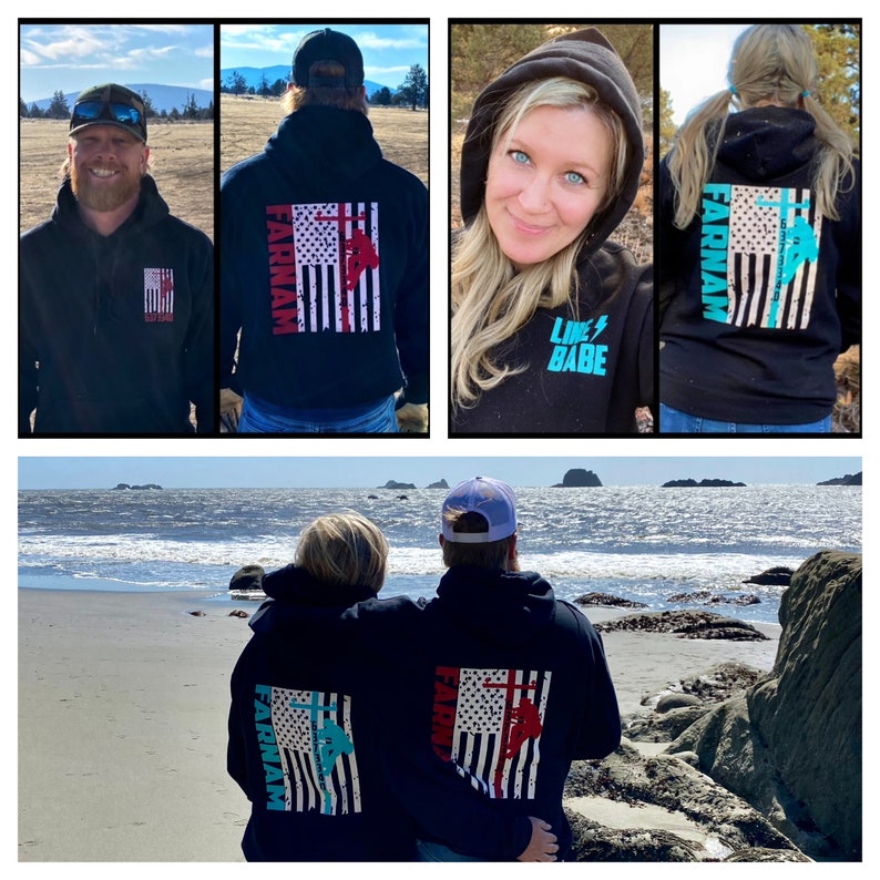 May include: A couple wearing black hoodies with a distressed American flag design on the back. The hoodies have the text "FARINAM" printed on the left side of the flag and a graphic of a lineman climbing a utility pole. The woman's hoodie has a turquoise blue and pink color scheme, while the man's hoodie has a red and white color scheme. The woman's hoodie also has the text "LINE BABE" printed on the front. The couple is standing on a beach with the ocean in the background.