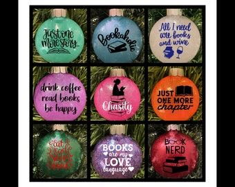 May include: Nine round Christmas ornaments with glitter finishes and black vinyl lettering. The ornaments feature book-themed sayings such as "Just one more story...", "Bookaholic", "All I need are books and wine", "Drink coffee read books be happy", "Chasity", "Just one more chapter", "Eat read sleep repeat", "Books are my love language", and "Book Nerd".