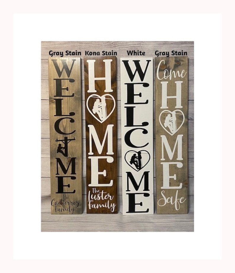 May include: Four wooden welcome signs with the word "WELCOME" spelled vertically. Each sign features a silhouette of a lineman in a heart. The signs are stained in grey, brown, white, and grey. The signs are personalised with the family names "The Gutierrez Family", "The Luster Family", and "Come Home Safe".
