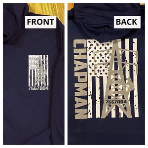 May include: A navy blue hooded sweatshirt with a white and gray American flag design. The flag features a power line tower with a worker climbing it. The text "CHAPMAN" and "7667804" are printed on the sweatshirt.