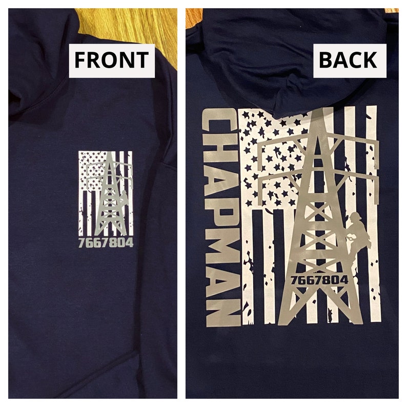 May include: A navy blue hooded sweatshirt with a white and gray American flag design. The flag features a power line tower with a worker climbing it. The text "CHAPMAN" and "7667804" are printed on the sweatshirt.