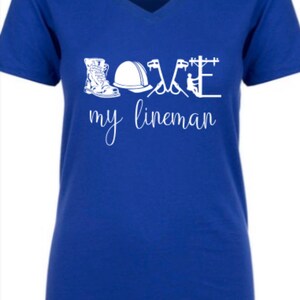 May include: A royal blue v-neck t-shirt with the words "LOVE my lineman" in white. The word "LOVE" is made up of images of a lineman's tools, including boots, a hard hat, and tools.