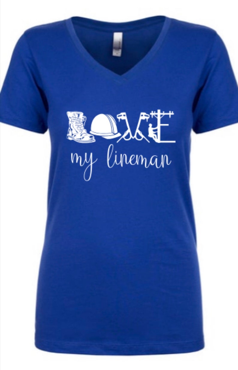 May include: A royal blue v-neck t-shirt with the words "LOVE my lineman" in white. The word "LOVE" is made up of images of a lineman's tools, including boots, a hard hat, and tools.