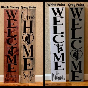 May include: Four wooden welcome signs with different paint colours and family names. The signs feature a silhouette of a lineman climbing a utility pole with a heart shape around it. The signs read "Welcome Home" with the family names "The Bans Family", "Safe", "The Morenos", and "Welcome".